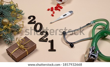New Year's card on medical subjects: figures 2021, phonendoscope, tablet with spruce branch on a beige background. New Year 2021 medicine.