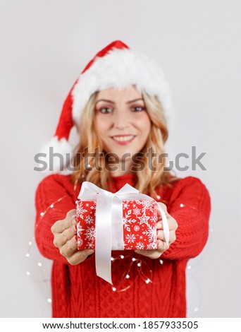 Smiling young woman in santa hat holding  out present