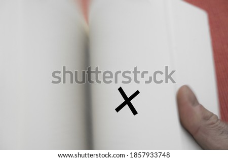 Concept read across book is quickly leafed through with the thumb blur due to movement and black cross as a bookmark