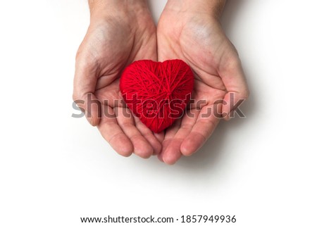 Closeup of a red heart in hands of man on white background