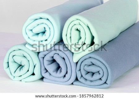 Rolls of knitted fabric of different shades, light blue, blue on a white background, close-up