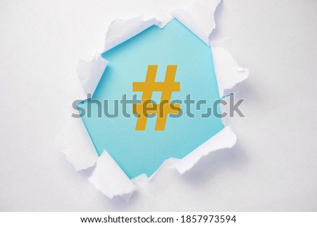 in the center of the torn white paper is a blue background with a hashtag in the color fortuna gold