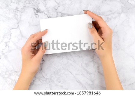 Beautiful womans hand with manicure holding business card. Office work concept.