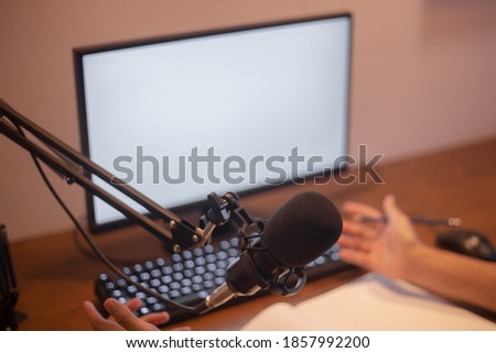 Asian man is recording voice for podcast video using home studio equipment.