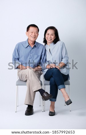 A couple of happiness asian old man and old woman sitting in studio white background. Isolated picture of smiling asian elderly man and woman in studio.