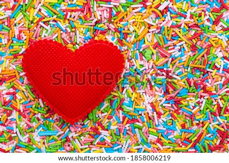 Red heart on a multicolored background of sweet cake powder.Greeting card on Valentine's day . 