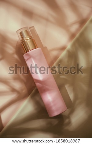Pink cosmetic beauty bottle from above on pastel background. Brand ad mockup. Lights and shadows from palm leaves. Copy space, minimalism beauty blogging flatlay concept