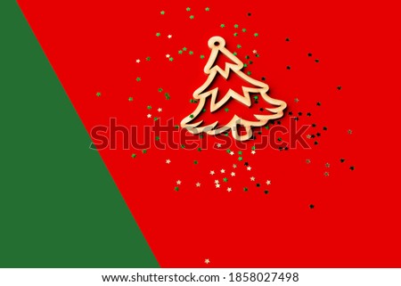 Wooden Christmas decor on a red and green background. Top view. Wooden Christmas tree and in confetti with copy-space.