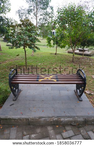 Alternative seating sign for social distancing rules on a long bench in the park
