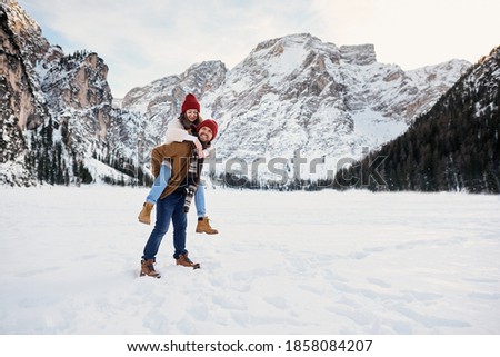 Couple of young people on winter vacation having fun on the background of alpine mountains.