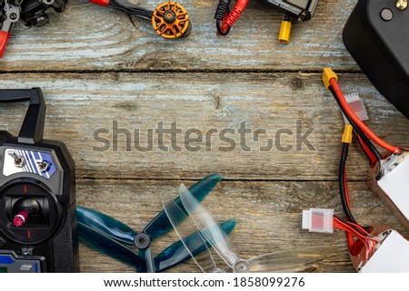Hobby drone racing concept. Drone, simulator cable and quadcopter propellers with a 5 cell battery layed out in a still life on an old wooden background. Copy space for text