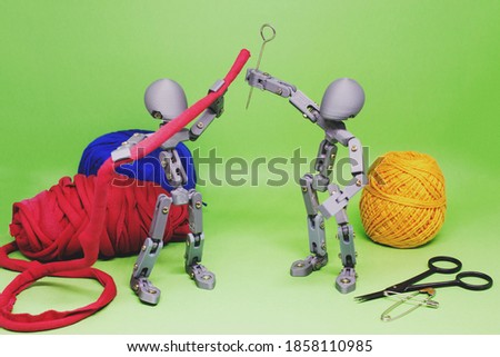Two articulated dolls, in cooperation, simulate the creation and development of some art project. In this still photography, toys and sewing materials were used to create the scene.