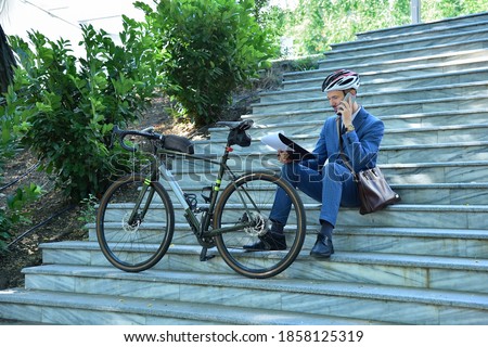 Businessman analyzes business report and talking on mobile phone with bike. Business and urban style concept