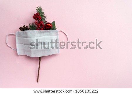 Single fir branches and medical mask on pink background. Christmas minimalism.