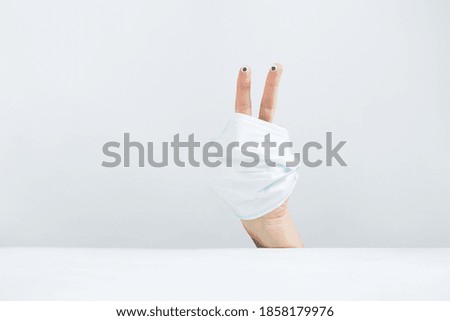 Face expression hand fingers with eyes concept with protective surgical mask