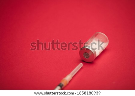 vaccine bottle with syringe, and red background
