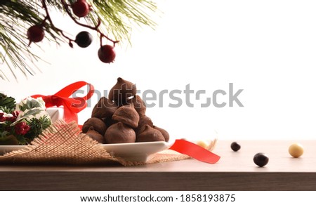 Christmas decorative centerpiece on wooden base with plate full of chocolate truffles with white isolated background. Front view. Horizontal composition.