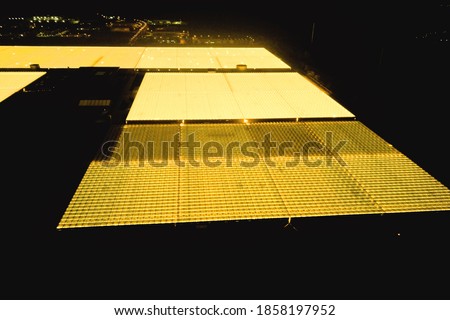 greenhouse glows bright yellow at night, aerial photography