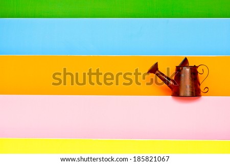 old watering can with colorful wood background