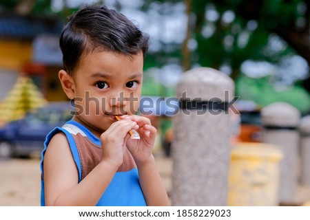 Happy-go-lucky boy eating chocolate at the park  Royalty-Free Stock Photo #1858229023