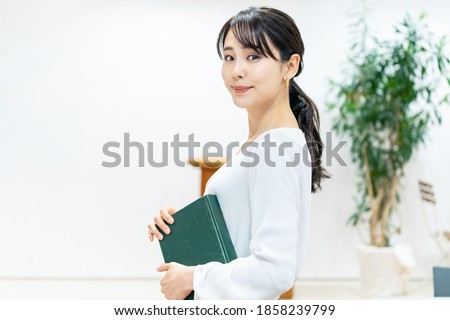 Young asian woman holding a book.