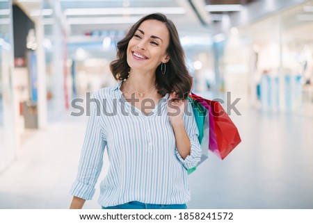 Confident happy attractive young woman walking through the mall with a bunch of shopping bags in hand.