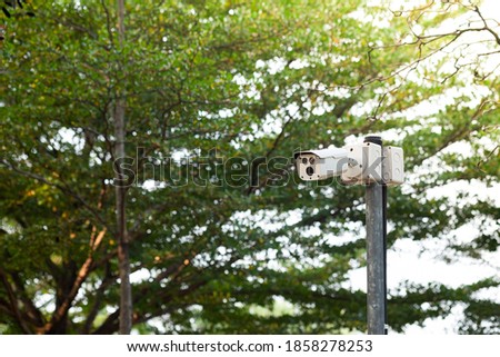 CCTV security camera on the pole with greenery background in the public park.