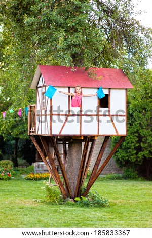 Cute small tree house for kids on backyard. Girl inside.