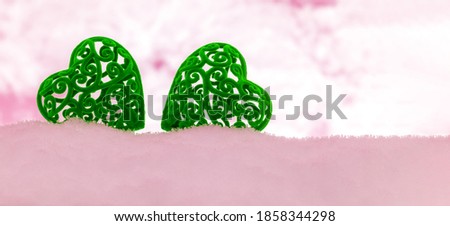 banner with two green velvet hearts in a pink snowdrift with a copy space