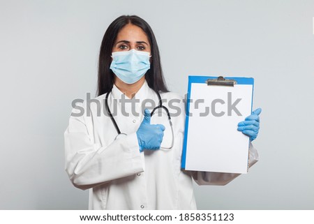 Doctor or medical staff in white gown with stethoscope around his neck holding document and showing ok sign, healthcare concept.