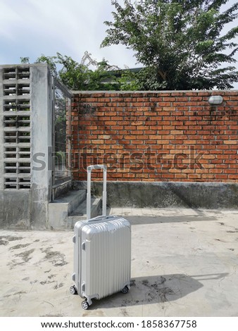 A silver suitcase in front of the bricks wall background