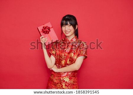 Portrait beautiful young Asian woman wear cheongsam  with red gift box for Chinese new year concept on a red background