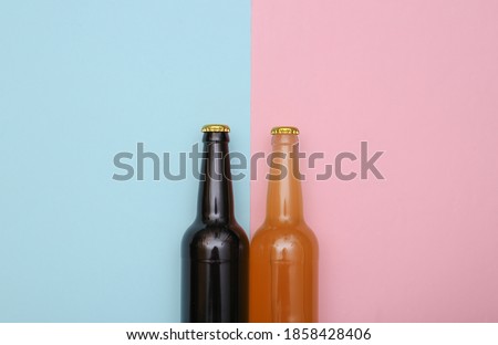 Bottle of light and dark beer on pink blue background. Top view
