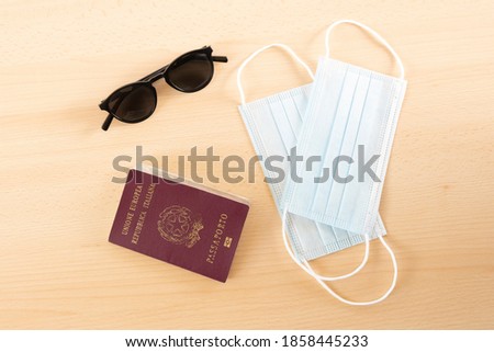 Travel concept, two face masks, sunglasses and a passport of the European Union are arranged on a wooden table. 