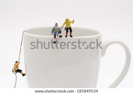 Miniature peoples climb up from coffee cup Royalty-Free Stock Photo #185849534
