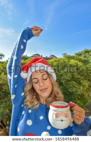 Girl having a coffee on the balcony wearing Christmas clothes.