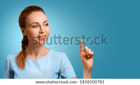 Poster with a young beautiful girl. The woman points her finger. Best deal. Space for advertising lettering. A woman on a blue background makes a choice.