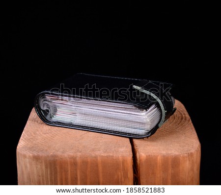 black leather business card holder on wooden stand and black background. copy space.