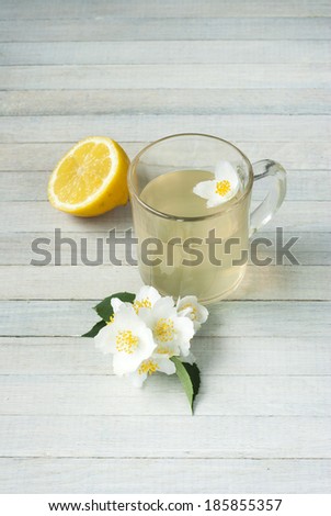 jasmine tea, jasmine flowers and lemon on bright wooden background