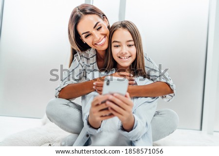 Smiling mother and daughter spend time together on the phone.