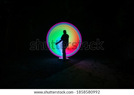 One person standing alone against red and green circle light painting as the backdrop