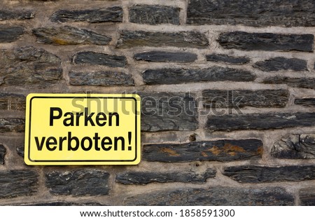 German yellow 'parken verboten' / parking not allowed sign on a brick wall.