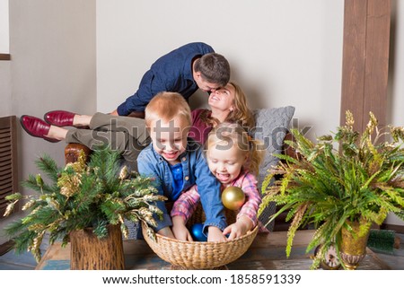 Happy parents are kissing while their small daugther and son play