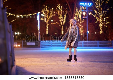 A young girl skating at ice rink on a beautiful magical night. Skating, hobby, winter