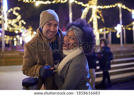A young couple posing for a photo at ice rink on a beautiful night. Skating, closeness, love, together
