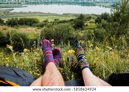 Couple's feet in funny socks. Boy and girl lying in tent. View from the open tent. Camping concept. Royalty-Free Stock Photo #1858624924