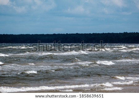 sea beach with white sand and blue water before storm. waves with white heads
