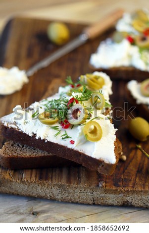 Selective focus. Macro. Mascarpone sandwiches with olives and spices.