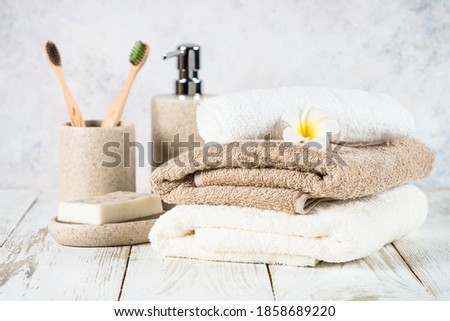 Bathroom background with ceramic soap and towels stack at white table.