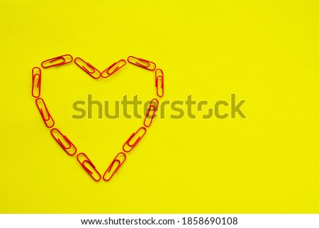 Heart shape made from paper clips on a yellow background. Valentine's day concept. High quality photo